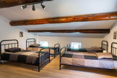 quatre lits dans une chambre avec poutres en bois dans l'établissement Mas authentique à Eygalières, à Eygalières