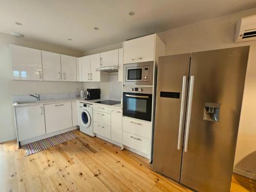 une cuisine avec des armoires blanches et un réfrigérateur en acier inoxydable dans l'établissement Sous les toits dans les nuages, à Dax