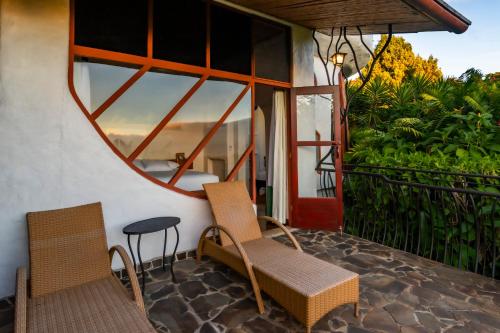 two chairs and a table on a balcony with a mirror at Finca Rosa Blanca Coffee Farm and Inn in Heredia