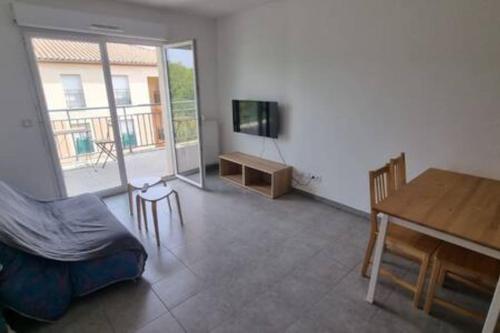 - un salon avec un lit, une table et une télévision dans l'établissement Le Pompéi, à Juvignac