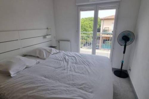 une chambre blanche avec un lit et une fenêtre dans l'établissement Le Pompéi, à Juvignac