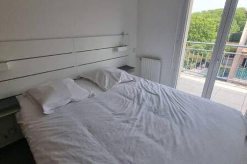 un lit blanc dans une chambre avec une fenêtre dans l'établissement Le Pompéi, à Juvignac
