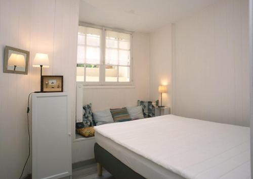 une chambre blanche avec un lit et une fenêtre dans l'établissement Petit Souplex dans l'hypercentre de Cabourg 80 m de la mer à pied, à Cabourg