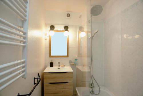 une salle de bain blanche avec un lavabo et une douche dans l'établissement Petit Souplex dans l'hypercentre de Cabourg 80 m de la mer à pied, à Cabourg