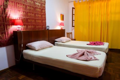 two beds in a hotel room with towels on them at O Jardim do Vinho, AC in Praia