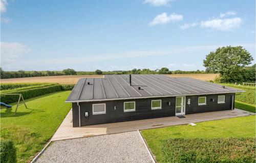a black house with a roof on a wooden deck at Lovely Home In Haderslev With Sauna in Store Anslet
