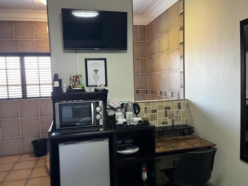 a kitchen with a microwave and a tv on a counter at Klyne Jiweel Guesthouse in Pretoria