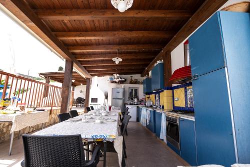 a kitchen with blue cabinets and a table with chairs at Villa Giulia Tonnara di Bonagia in Valderice