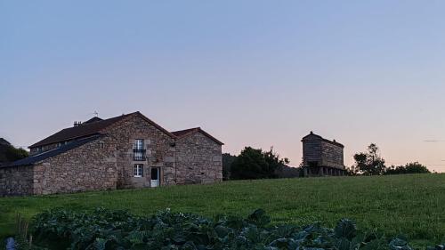 an old stone house and a silo in a field at Casa de Valente - Camariñas in Camariñas