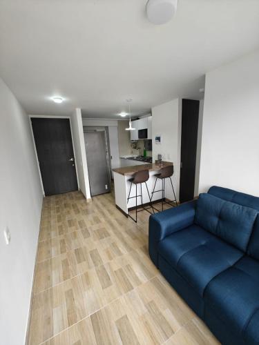 a living room with a blue couch and a kitchen at Apartamento Para Estrenar En Toberin Norte De Bogota Piso 17 in Bogotá