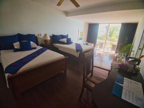 a bedroom with two beds and a desk and a window at Blue Haven Hotel - Bacolet Bay - Tobago in Scarborough