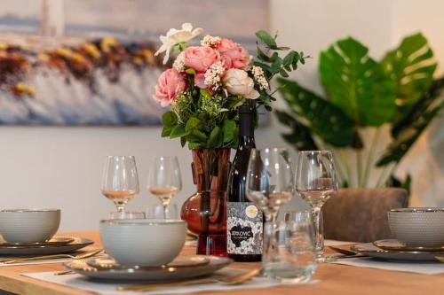 a table with a vase of flowers and wine glasses at Luxury Penthouse - Views, Hot Tub & Pool in Makarska