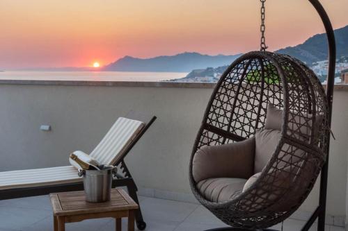 a swing chair on a balcony with a sunset at Luxury Penthouse - Views, Hot Tub & Pool in Makarska