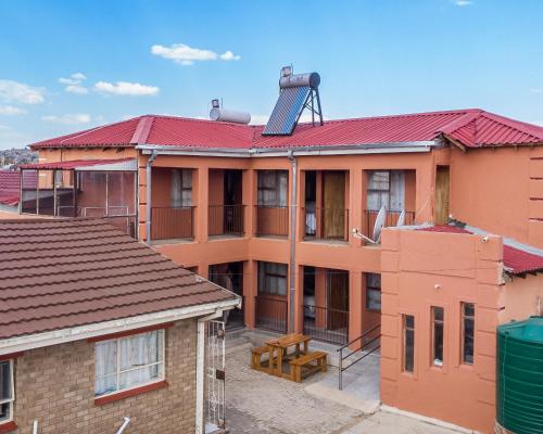 an apartment building with a red roof with a solarvisor at Vochelo Lodge in Phuthaditjhaba