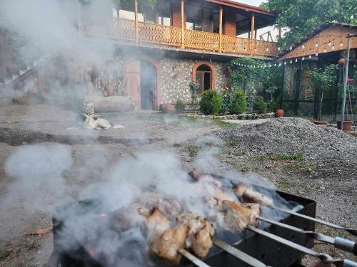 a grill with smoke in front of a house at Lomtadze Family Wine Hotel in Ambrolauri