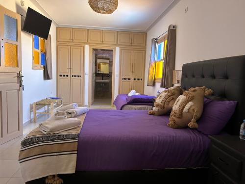 a bedroom with two beds with purple comforters at Riad Ghazal in Essaouira