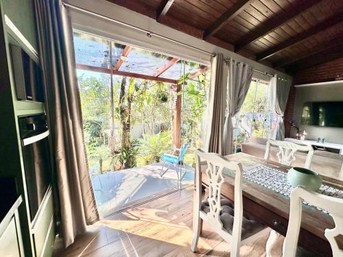 a dining room with a table and chairs and a large window at RECANTO DOS PASSARINHOS LINDA CASA COM 2 quartos in Balneário Camboriú