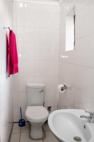 a white bathroom with a toilet and a sink at Vochelo Lodge in Phuthaditjhaba