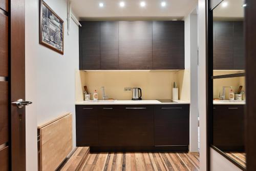 Modern Studio-apartment in the centre في ريغا: مطبخ بدولاب سوداء وارضية خشبية