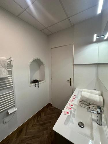 une salle de bain blanche avec un lavabo et un miroir dans l'établissement Appartement du Cloitre 1er, à Narbonne