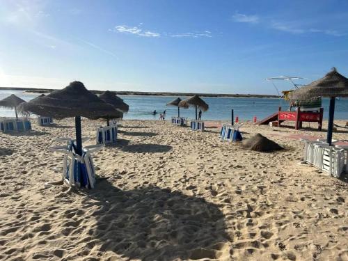 a sandy beach with umbrellas and chairs and the ocean at Seaview Villa with Private Pool in Moncarapacho in Moncarapacho