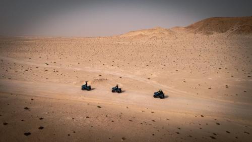 two people riding motorcycles in the desert at La Crique Nature & Spa in Dakhla