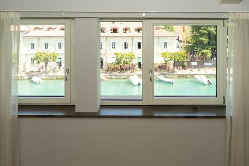 two windows in a room with a view of the water at C House Rooms Lake in Peschiera del Garda