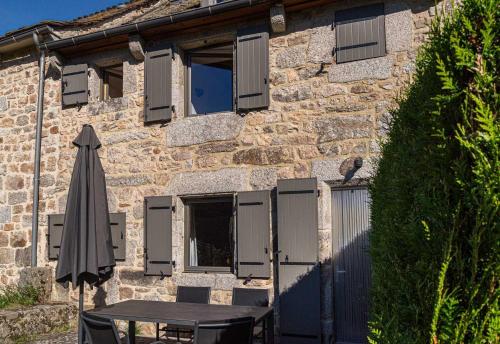 a table and an umbrella in front of a building at Gîte Gîtes de France 4/6 personnes A in La Fage-Saint-Julien