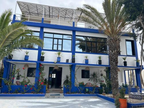 a blue and white house with palm trees in front at Riad Ghazal in Essaouira