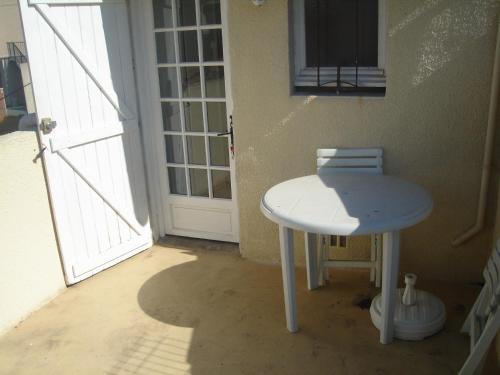 une table blanche et un tabouret devant une porte dans l'établissement STUDIO VALRAS Plage, à Valras-Plage