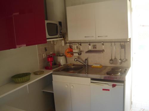 une petite cuisine avec des armoires blanches et un évier dans l'établissement STUDIO VALRAS Plage, à Valras-Plage