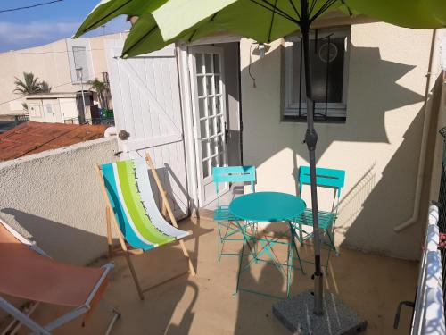 a patio with a table and chairs and an umbrella at STUDIO VALRAS Plage in Valras-Plage