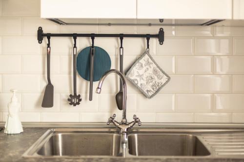 a kitchen sink with utensils hanging on a wall at Palinuro Casa Vacanza Melita in Palinuro
