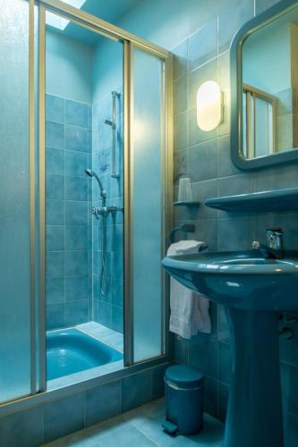 La salle de bains bleue est pourvue d'un lavabo et d'une douche. dans l'établissement Bon aubrac pour 12 personnes, à Les Hermaux