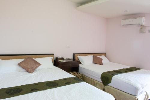 two beds in a room with white walls at Come and go seaside B&B in Fengbin