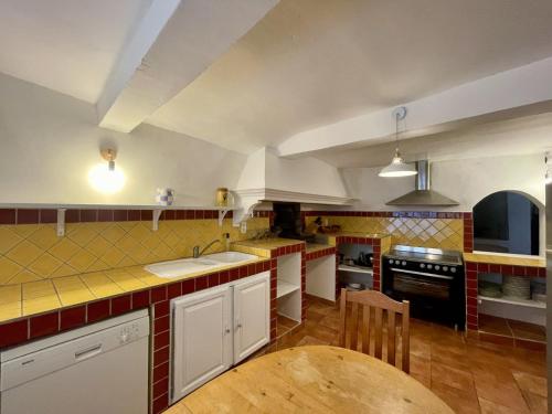 a kitchen with white cabinets and a wooden table at La Villageoise in Aups