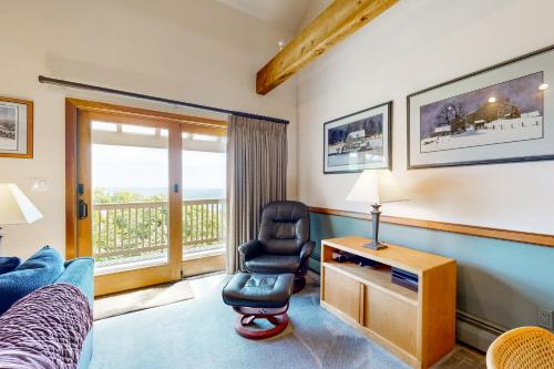 a bedroom with a chair and a desk with a window at Okemo Trailside 36E in Ludlow