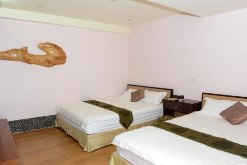 two beds in a room with white walls at Come and go seaside B&B in Fengbin