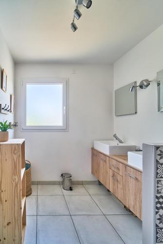 une salle de bain blanche avec un lavabo et une fenêtre dans l'établissement Charmante maison moderne à deux pas de la mer !, à Lancieux