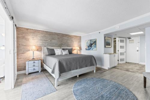 een slaapkamer met een bed en een houten wand bij New Oceanview Suite - Caravelle 504 in Myrtle Beach
