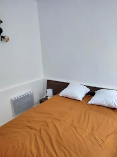 - une chambre avec un lit orange et 2 oreillers dans l'établissement Charmant T2 au cœur de Narbonne, à Narbonne
