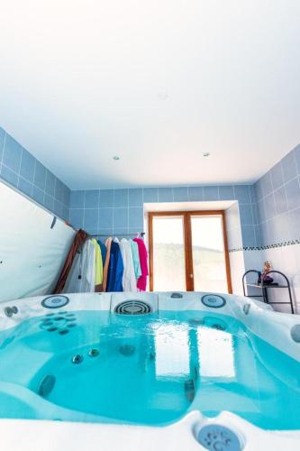 La salle de bains est pourvue d'une grande baignoire bleue et d'une fenêtre. dans l'établissement Gîte La Maison de Marie 6/8 personnes, à La Canourgue