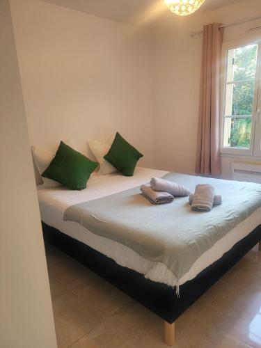 - un lit avec des oreillers verts dans l'établissement La Villa Sable en Provence, à Saint-Saturnin-lès-Apt