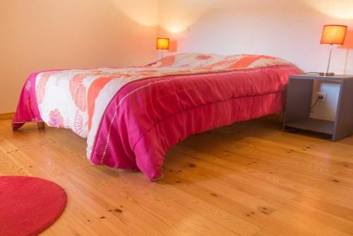 a bedroom with a bed with a pink comforter at Gite la bergerie au domal in La Canourgue