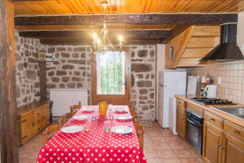 une cuisine avec une table avec une nappe rouge et blanche dans l'établissement Gîte Gîtes de France 6/8 pers à La Bessière, à Saint-Jean-Chazorne