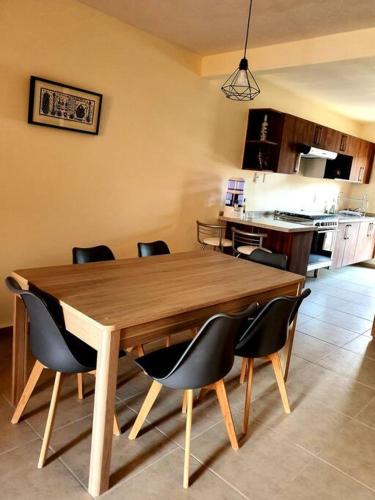 a wooden table in a kitchen with chairs around it at Departamento Casa Oaxaca SMA Pool Rooftgarden in San Miguel de Allende