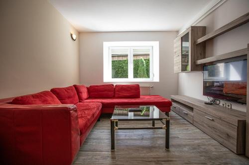 a living room with a red couch and a tv at Apartments Bells of Ljubljana - 3 cosy apartment Private Free Parking in Ljubljana