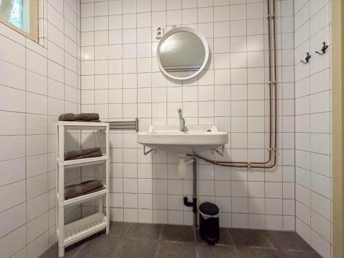 a white tiled bathroom with a sink and a mirror at Aarde in Lage Zwaluwe