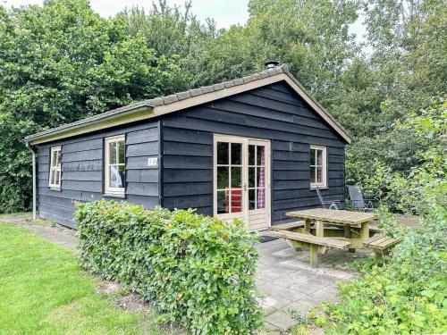 a black shed with a picnic table and a bench at Aarde in Lage Zwaluwe