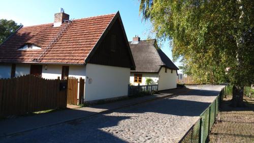 Casa blanca con techo marrón y valla en Haus am Wiek, en Krummin